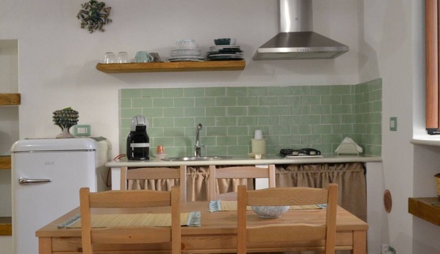Salvia is an independent loft located on the ground floor, featuring a small private courtyard furnished with chairs and a table. The space consists of an open-plan area with a sofa bed and equipped kitchen, as well as a spacious bathroom with a shower.